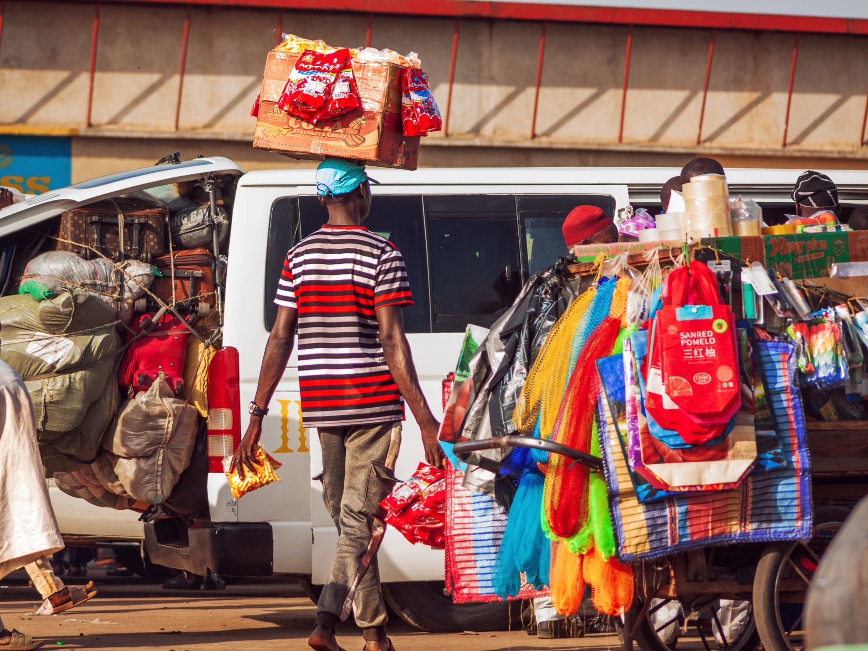 A snapshot of a bustling market scene with a vendor balancing goods on his head, highlighting vibrant street life.